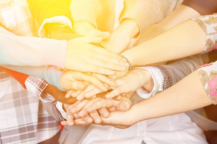 Viele Menschen legen ihre Hände übereinander