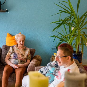 Bewohner des Lukashauses sitzen im Wohnzimmer zusammen auf dem Sofa