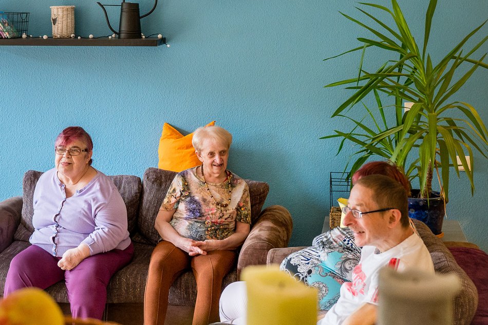 Bewohner des Lukashauses sitzen im Wohnzimmer zusammen auf dem Sofa