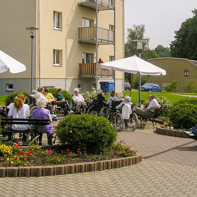 Bewohner sitzen im Sommer vor dem Haus des Betreuten Wohnens