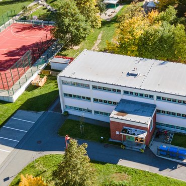 Luftbild der Kita Regenbogen mit angrenzendem Gelände und Sportplatz