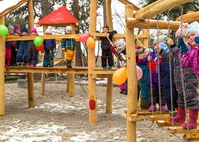Viele Kinder aus dem Kindergarten stehen auf einem Holzklettergerüst