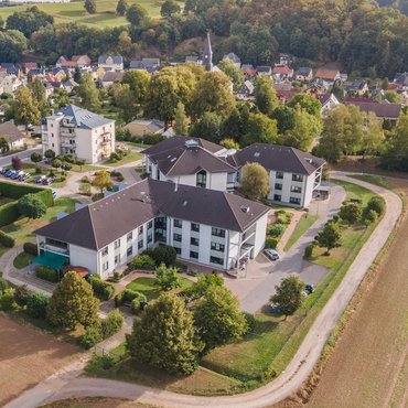 Luftbild des Jakobushaus in Mülsen Luftaufnahme vom Jakobushaus mit weißer Fassade und dunkelgrauem Dach. Im Hintergrund ist die Kirche St. Jacob und Häuser von Mülsen zu sehen.