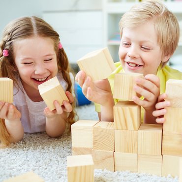 Ein Junge und zwei Mädchen spielen mit Bauklötzen