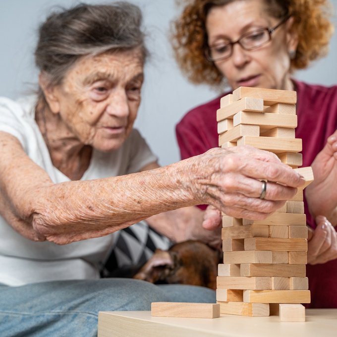 Seniorin und Nachbarschaftshelferin spielen gemeinsam Jenga 