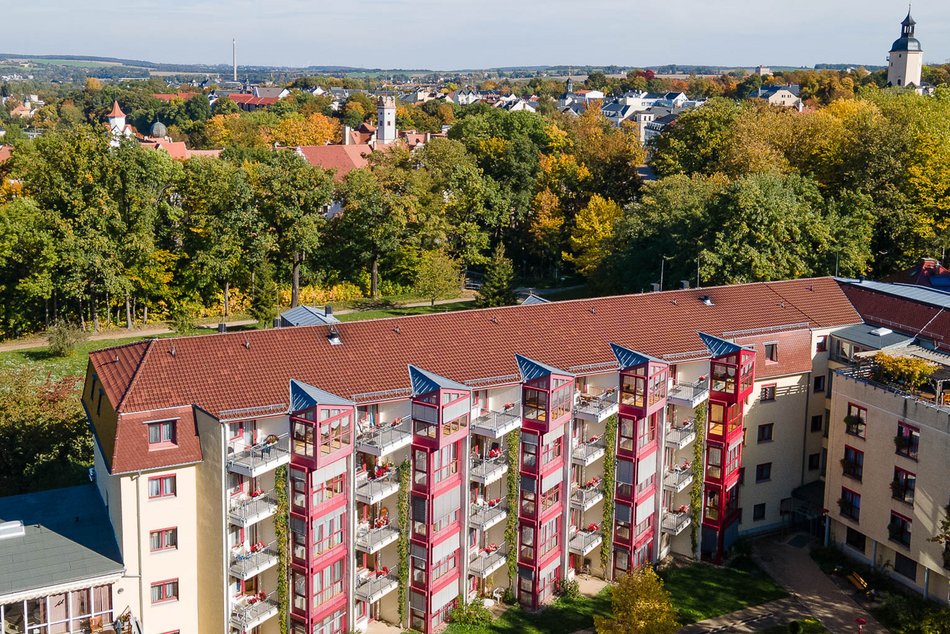 Luftbild des Haus Heinrichshof, an der Fassade sind zahlreiche kleine Balkone und Wintergärten der Bewohnerzimmer zu sehen, im Hintergrund ist Glauchau mit Schloss und Kirche zu sehen 