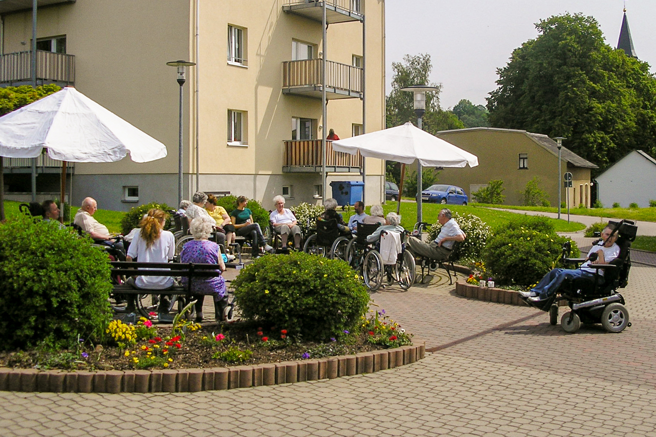 Bewohner sitzen im Sommer vor dem Haus des Betreuten Wohnens