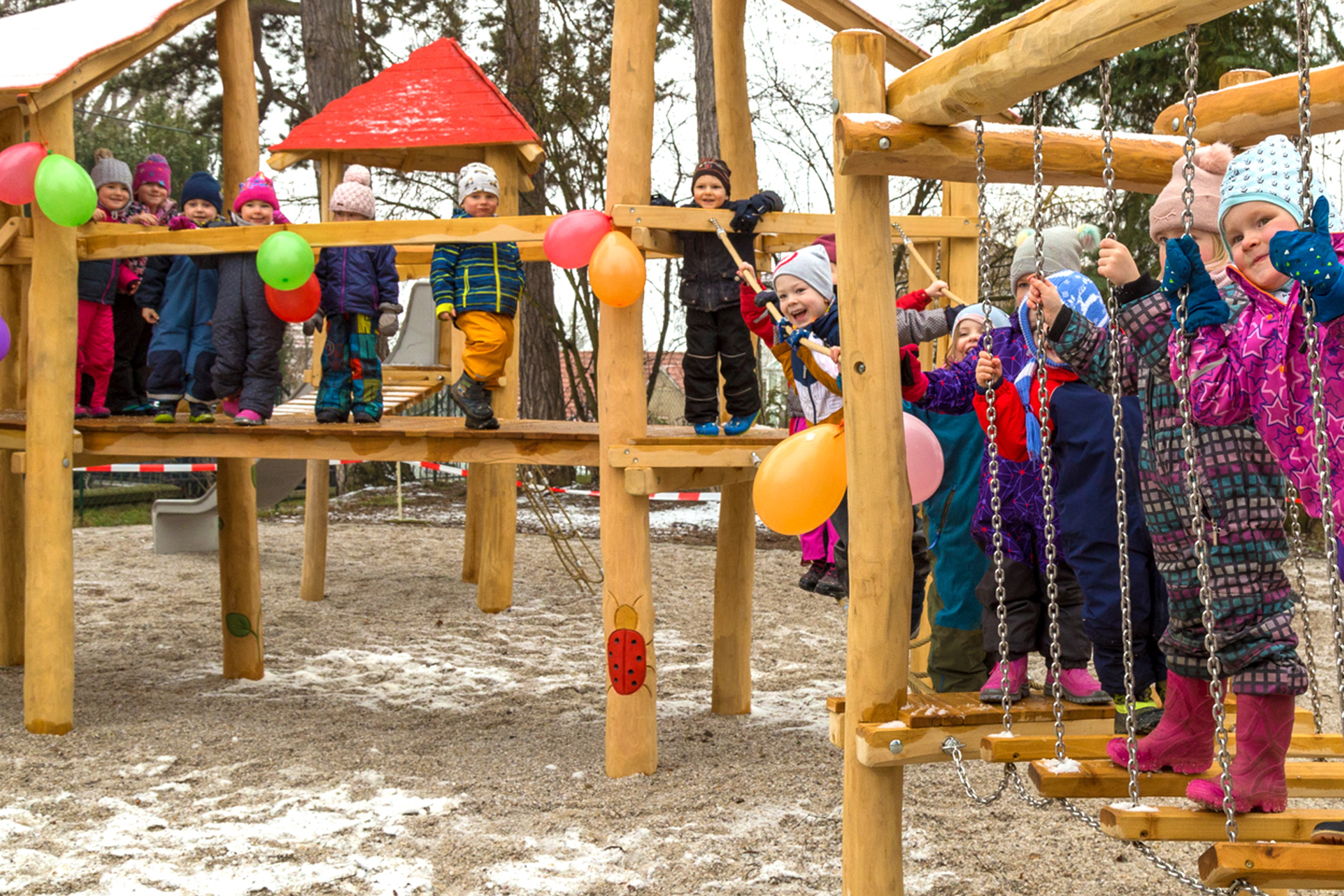Viele Kinder aus dem Kindergarten stehen auf einem Holzklettergerüst
