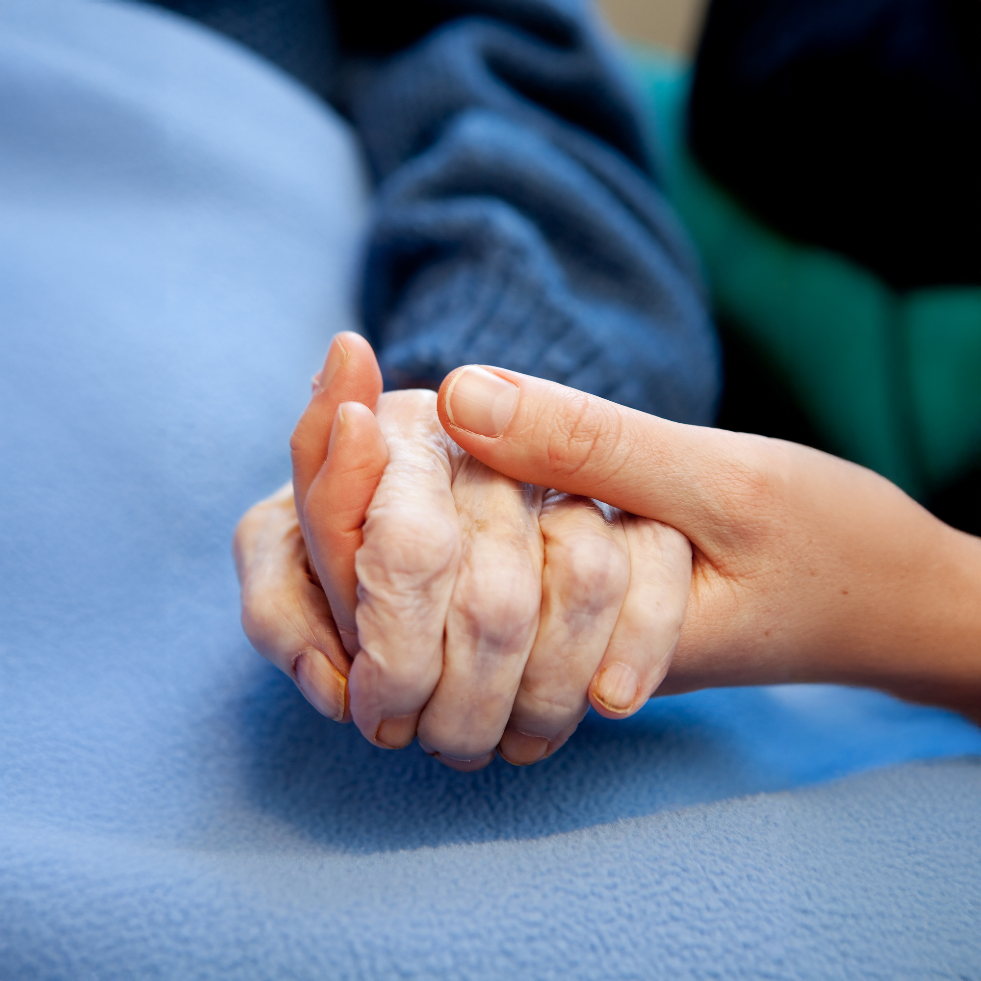 Eine junge Hand hält die Hand eines alten Menschen
